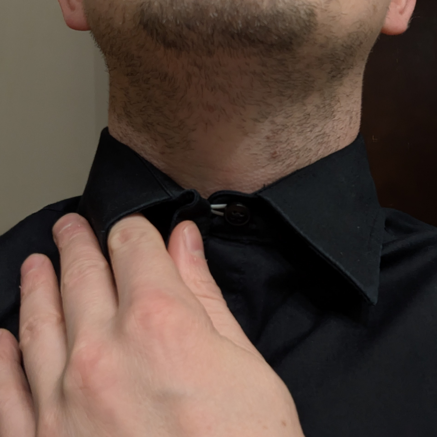 Close-up of a person wearing a collar extender, holding the fabric back to reveal its seamless functionality and added comfort.